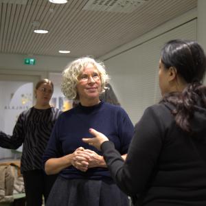 A blonde-haired woman and a dark-haired woman are talking to each other.