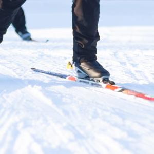 Hiihtäjän sukset aurinkoisella ladulla.