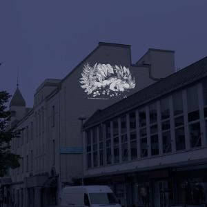 Havainnekuva katunäkymästä, jossa talon seinälle on heijastettu muumikuvitus.