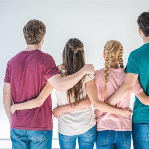 Neljä nuorta on selin katsojaa kohti. He pitelevät toisistaan kiinni kädet selkäpuolella.