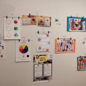Vaalealla seinällä on mm. värikkäitä lasten tekemiä kollaaseja ja väriympyrä.