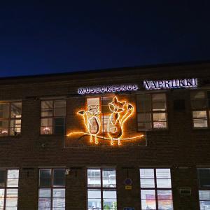 Vapriikin ulkoseinällä eläinvalohahmoja: lintu, kaksi kettua ja siili. Rakennuksen ikkunoista loistaa valoa pimeässä illassa.