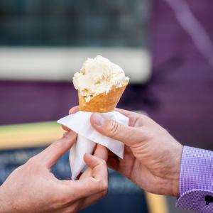 The picture shows two hands, one of which is handing the other an ice cream cone.