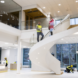 Kaksi henkilöä seisoo korkean aulatilan kaarevissa portaissa.