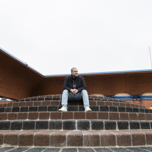A person is sitting on the steps in front of a red brick building.