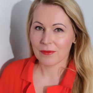 Irene katsoo suoraan kameraan kirkkaanpunainen paita päällään.