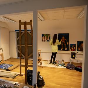 Taiteilija maalaa teosta työhuoneellaan.