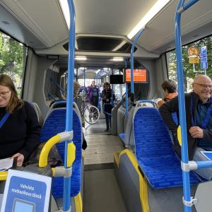 Asiakkaat testaavat superbussia ja täyttävät lomakkeita.