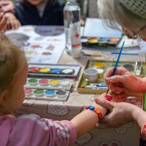 Ikäihminen maalaa lapsen kanssa