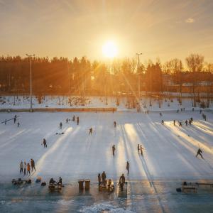 Sorsapuiston ulkojäällä ihmisiä ja laskevan auringon valo. 