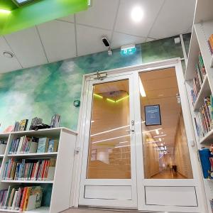 Musta-valkoinen kävijälaskuri kirjaston lasiovien oviaukon yläpuolella.