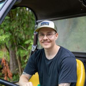 Henkilö istuu työkoneen kyydissä ja nojaa toisella kädellään rattiin.