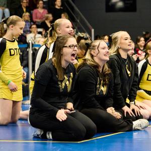 Urheilijoita kannustamssa istuen salin reunalla 