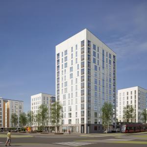 Kuvassa kerrostaloja, torni keskellä, puita.