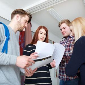 Neljä nuorta seisomassa ja katsomassa papereita