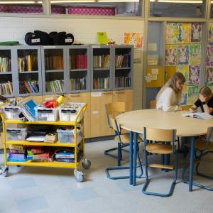 Kaksi opettajaa auttaa oppilasta läksyjen kanssa koulussa.