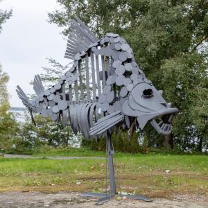 Kalaa esittävä metallinen veistos seisoo nurmikolla. 