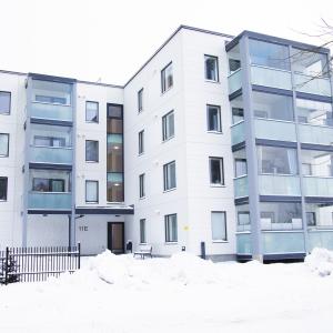 Valkoinen kerrostalo, jossa on lasitetut parvekkeet.