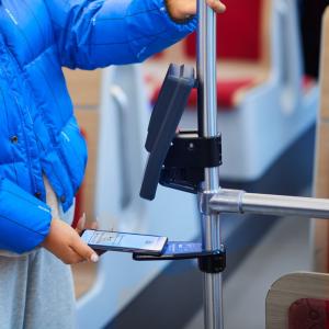 Matkustaja näyttää mobiililippunsa ratikan lukulaitteelle.