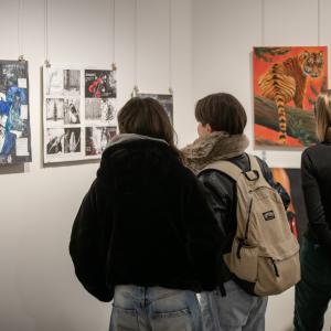 Kolme henkilöä katsoo näyttelyä galleriassa