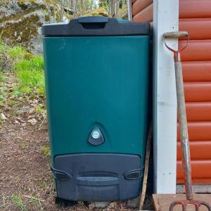 Vihreä biojätekompostori talon nurkalla.