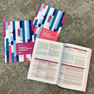 Kolme kirjaa matolla, joista yksi on keskiaukeamalta auki.