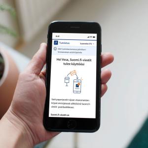 Ihmisellä kädessään puhelin, jonka avulla hän on tunnistautumassa suomi.fi-palveluun..