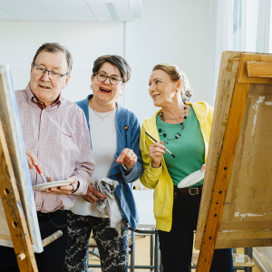 Three people are standing next to their easels.
