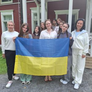 Johanna Kirjavainen stands with young people from Kiova, holding the Ukrainian flag, at the Sorja summer camp.