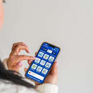 A woman with pink artificial nails is using the Tampere.Finland app on her phone.