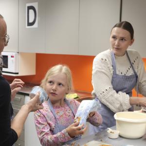 Kotitalousopettaja neuvoo äitiä ja tytärtä Perheköksässä kasviruoan tekemisessä.