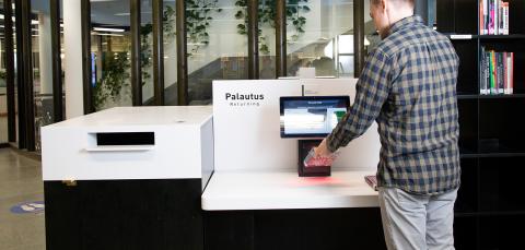 Henkilö palauttaa kirjaa palautuspisteellä.