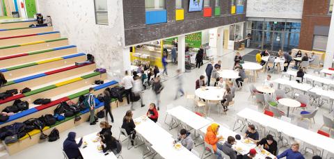 Kuva Tesoman koulun aulasta, jossa oppilaat ovat ruokailemassa.