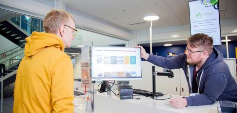 Asiakas ja virkailija katsovat yhdessä näyttöä.