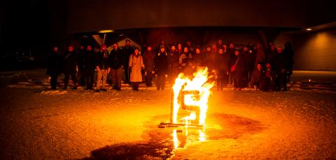 Taidekaaren ohjaajat ulkona illan hämyssä tulitaideteoksen äärellä.