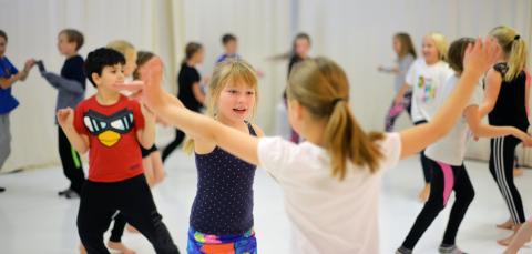 Lapsia tanssimassa vauhdikkasti tanssisalissa.