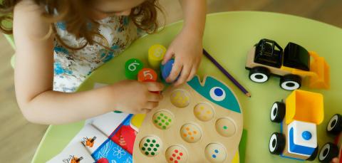 Lapsi tekee pöydän ääressä kalan muotoista numeropalapeliä.