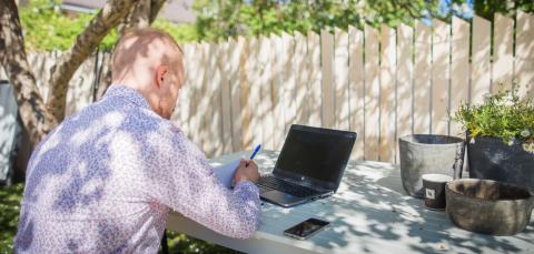 Mies kesällä tietokoneen ääressä.