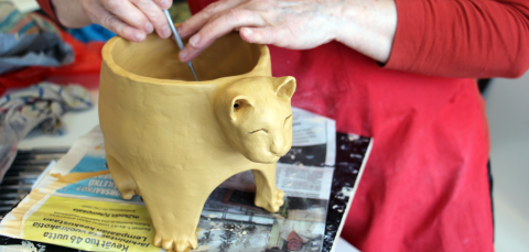 Henkilön kädet, jotka viimeistelevät keramiikkatyötä.