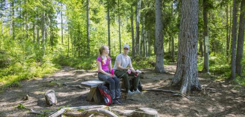 Retkeilijät istuvat penkillä Koukkujärven luontopolulla.