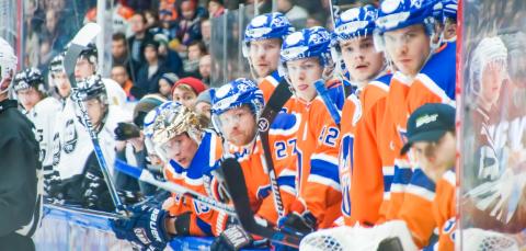 Vaihtoaitiossa olevat jääkiekkoilijat seuraavat peliä.