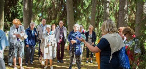 Opas kertoo historiasta metsässä olevalle ihmisjoukolle.