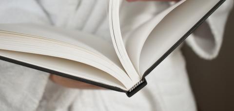 Henkilö pitää kädessään avointa kirjaa.