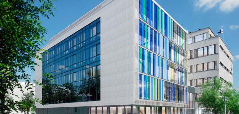 Kadun varrella olevassa valkoisessa rakennuksessa on isot ikkunat.