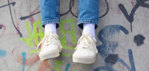 Nuoren jalat, taustalla betoniseinä, jossa graffiteja.
