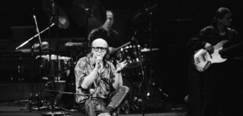 Juice istuu tuolilla ja laulaa mikrofoniin Tampere-talon lavalla.