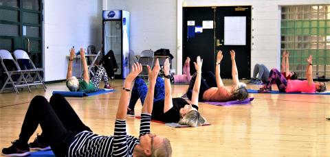 People stretching on exercise mats at a gym.