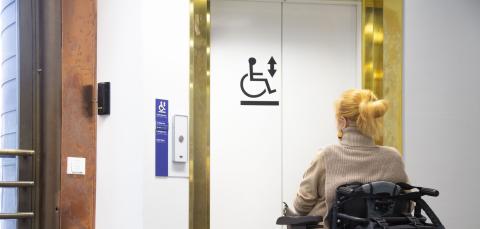 Pyörätuolia käyttävä henkilö odottaa hissiä.