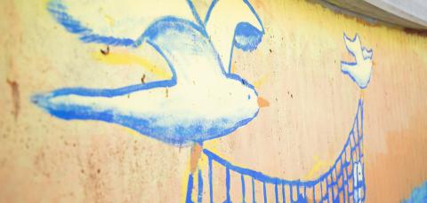 Muraali, jossa kaksi lintua kantaa verkkoa.