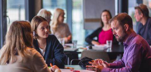 Ihmisiä keskustelemassa yhdessä pöydän äärellä.